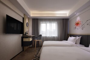 A hotel room with a flat-screen TV, a desk with a chair, a bed with white bedding, a large window with curtains, and a wall-mounted clock. - Paco Hotel Jiangtai Lu Metro Guangzhou (Guangzhou)