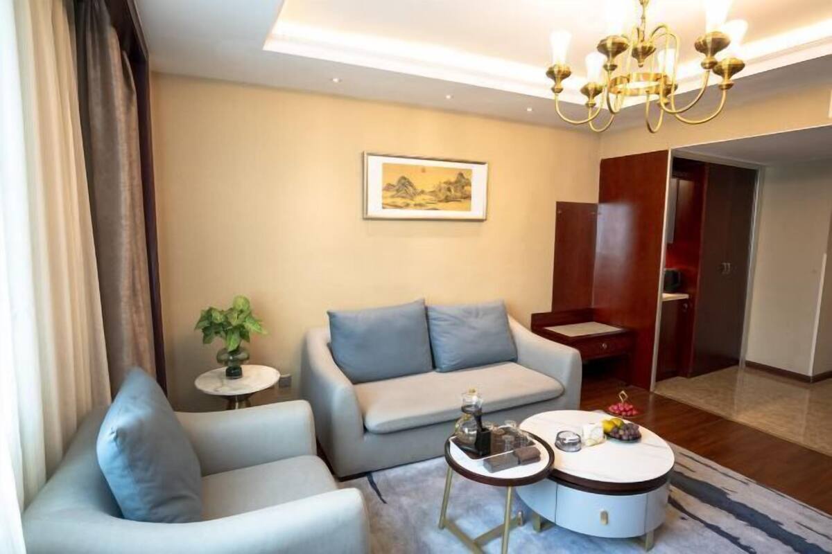 A modern living room with a sofa, a coffee table, and a chandelier.