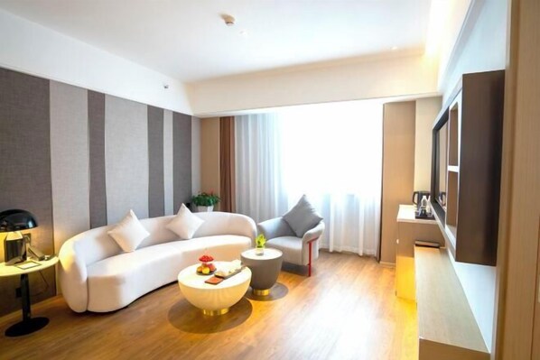 A modern living room with a sofa, two coffee tables, and a flat-screen TV. - Zijin Hotel (Shanghang)
