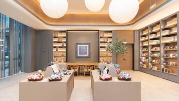 A modern library with bookshelves, a central table, and two seating areas.