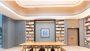 A modern conference room with a long table, chairs, bookshelves, and a framed picture on the wall. - Ji Hotel Nanjing South Railway Station Square (Nanjing)