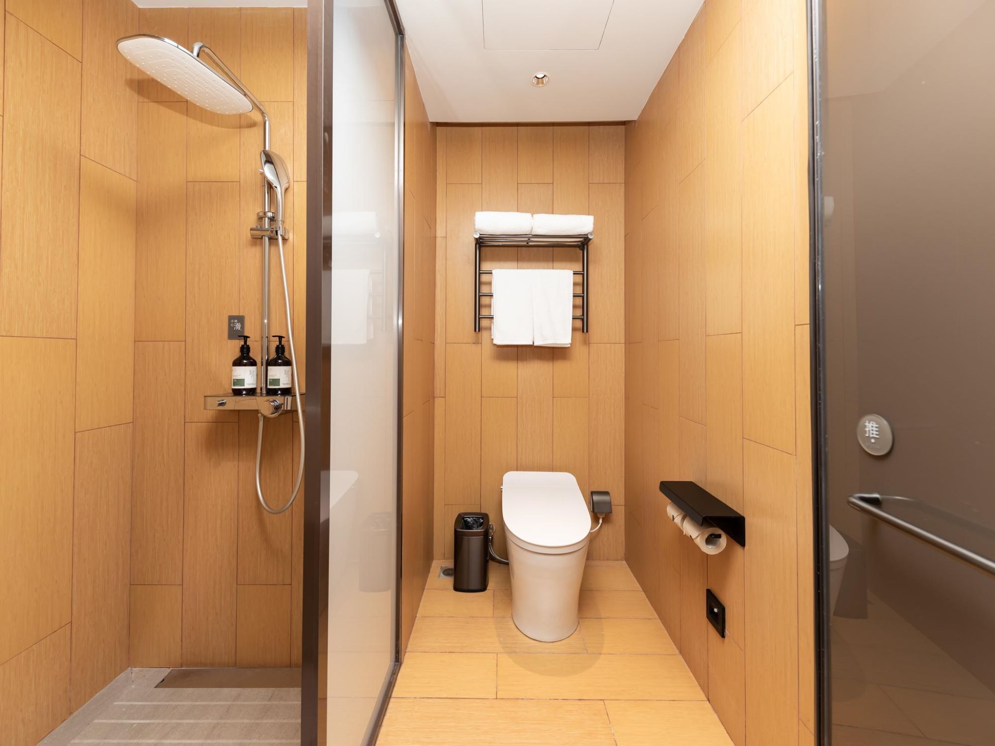 Un baño moderno con ducha, inodoro y un perchero para toallas.
