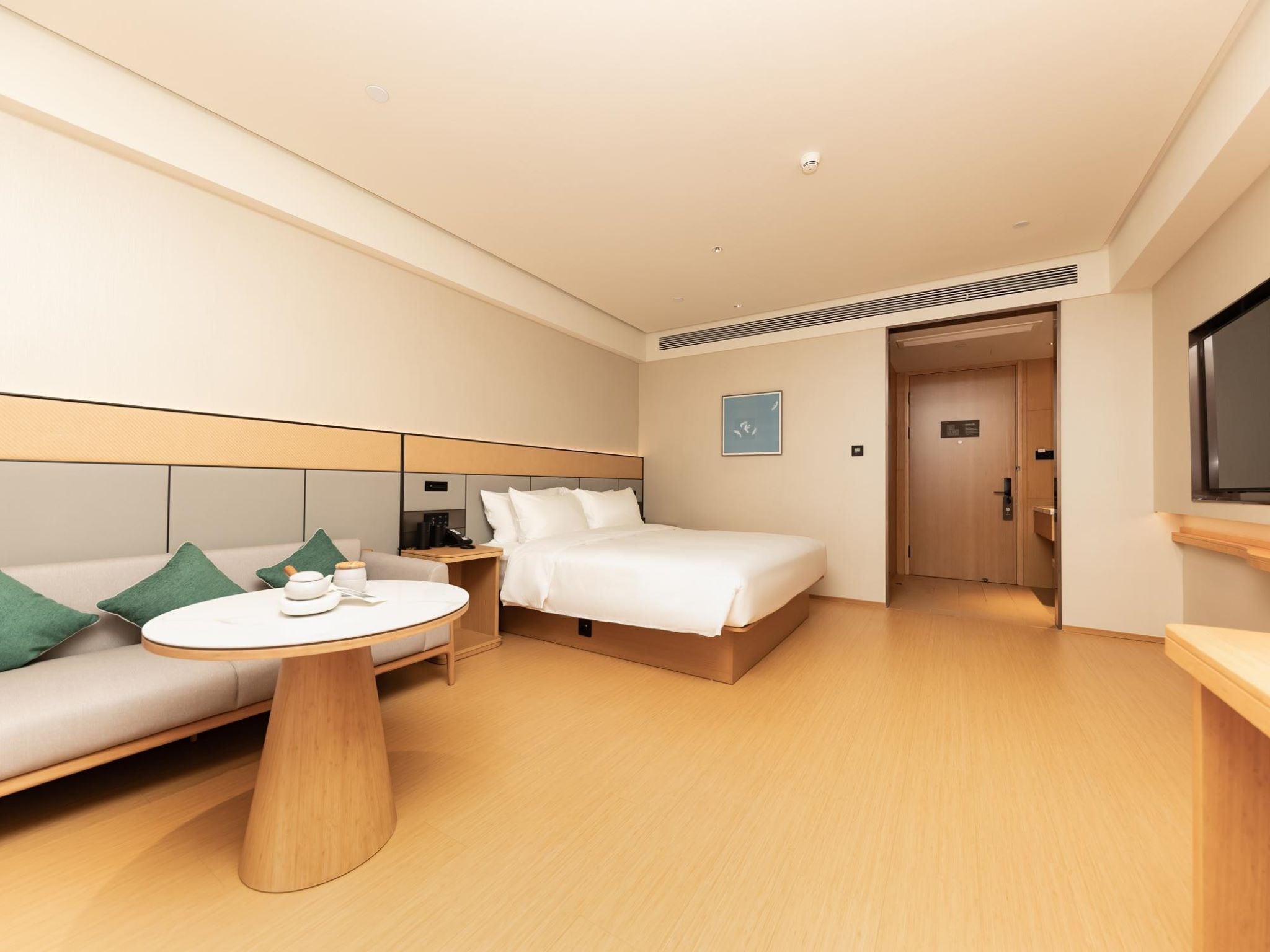 Una habitación de hotel con cama, sofá, mesa redonda y televisor.