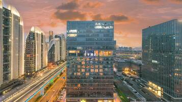 A modern hotel with a glass facade, multiple floors, and a prominent entrance.