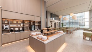 A modern cafe with a central island, seating area, and a large window. - Ji Hotel Nanjing South Railway Station Square (Nanjing)