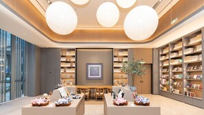 A modern library with bookshelves, a central table, and two seating areas. - Ji Hotel Nanjing South Railway Station Square (Nanjing)