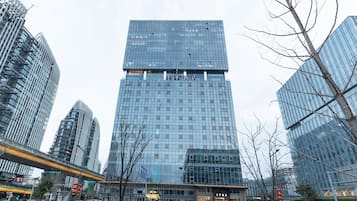 A modern high-rise hotel with a glass facade, multiple floors, and a prominent entrance.