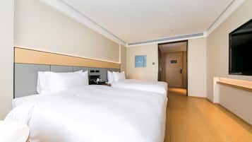 A hotel room with a large bed, bedside tables, a TV, and a door leading to another room.