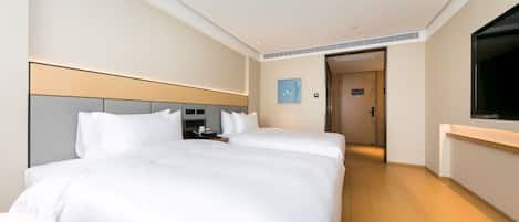 A hotel room with a large bed, bedside tables, a TV, and a door leading to another room.