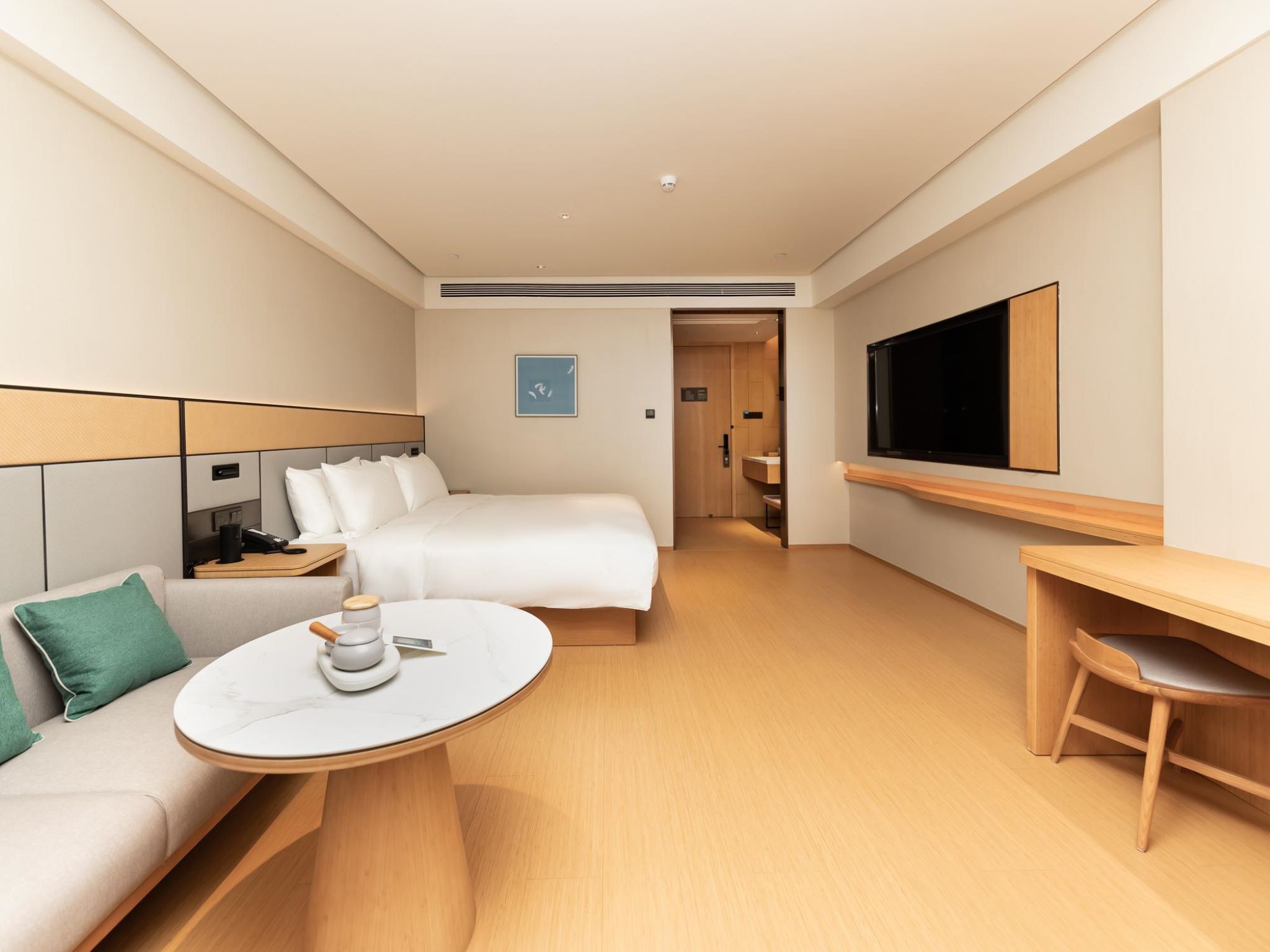 Ein Hotelzimmer mit Bett, Schreibtisch, Fernseher, Couchtisch und Sofa.