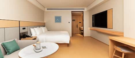 A hotel room with a bed, a desk, a TV, a coffee table, and a sofa.