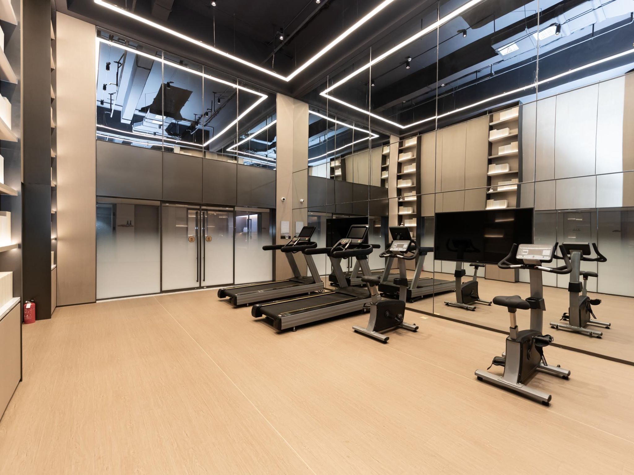 Un gimnasio moderno con cintas de correr, elípticas y un espejo grande.