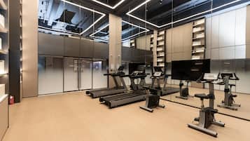 Un gimnasio moderno con cintas de correr, elípticas y un espejo grande.