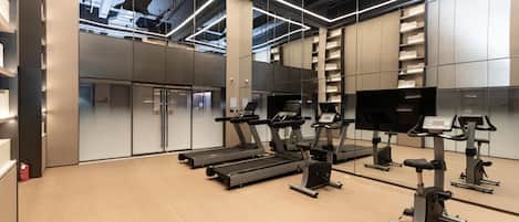 Un gimnasio moderno con cintas de correr, elípticas y un espejo grande.