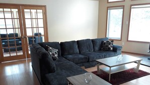 A living room with a dark grey sectional sofa, two white coffee tables, and a red rug.