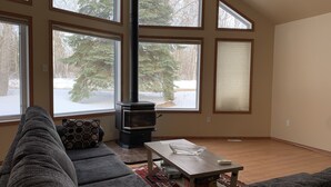 A living room with a large window, a fireplace, a sofa, and a coffee table.