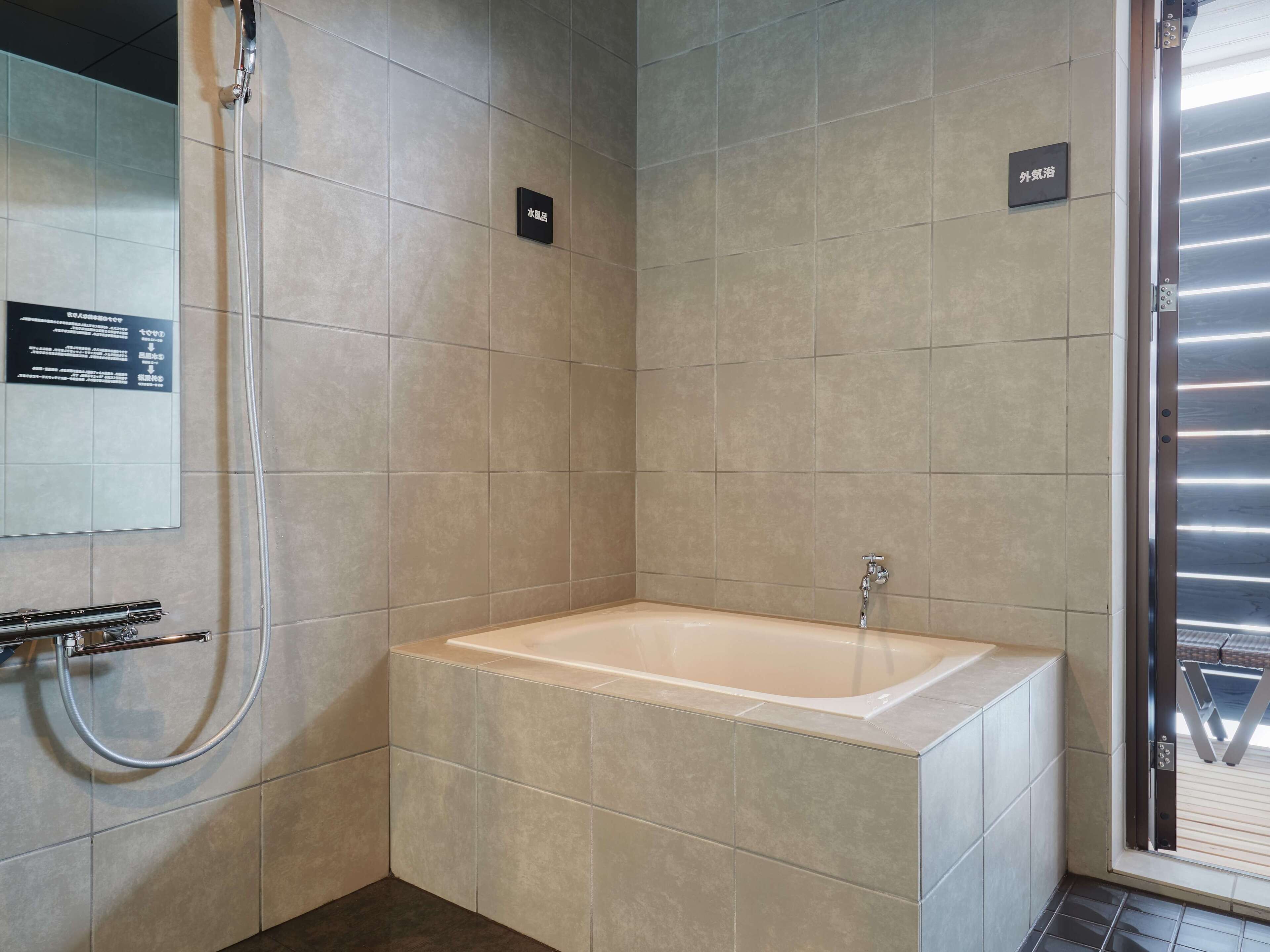 A modern bathroom with a bathtub, a shower, and a toilet. There are signs indicating the location of each fixture.