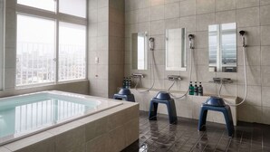 A modern bathroom with a large bathtub, two mirrors, and a window with a city view. - CABIN&HOTEL CONSTANT NAHA (Naha)