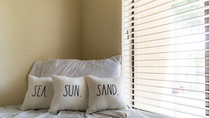 A bed with three pillows labeled "SEA," "SUN," and "SAND."