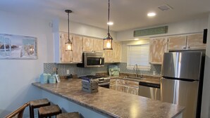 A kitchen with wooden cabinets, stainless steel appliances, and a large island with bar stools.
