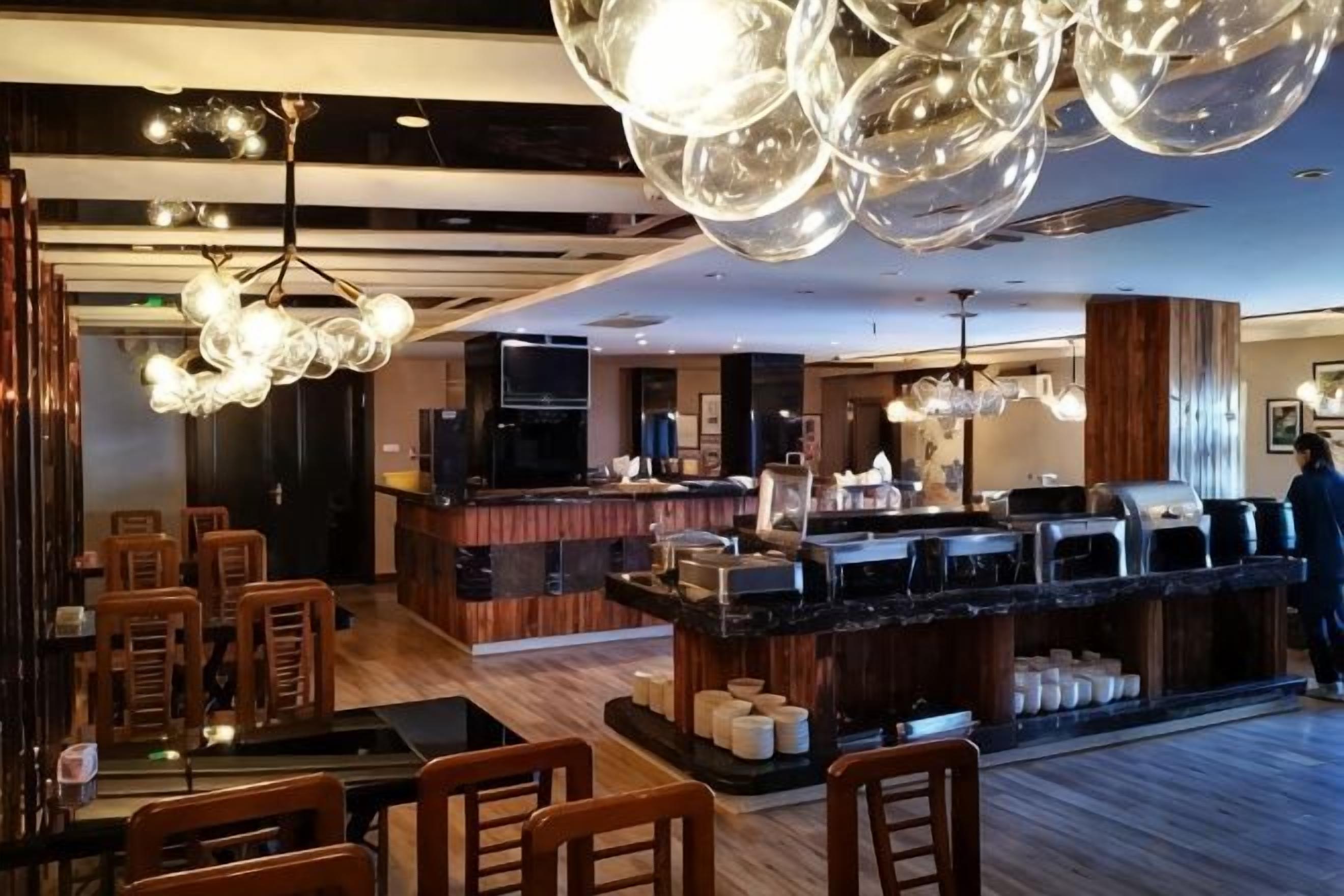 A hotel lobby with a bar area, seating, and a large chandelier.