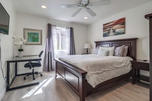 A bedroom with a bed, desk, chair, and a ceiling fan.
