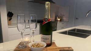 Un comptoir de cuisine avec une bouteille de champagne Duperrey, deux verres, une bougie et un bol de noix.