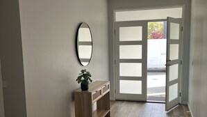 Un couloir avec une console en bois, un miroir et une porte donnant sur l’extérieur.