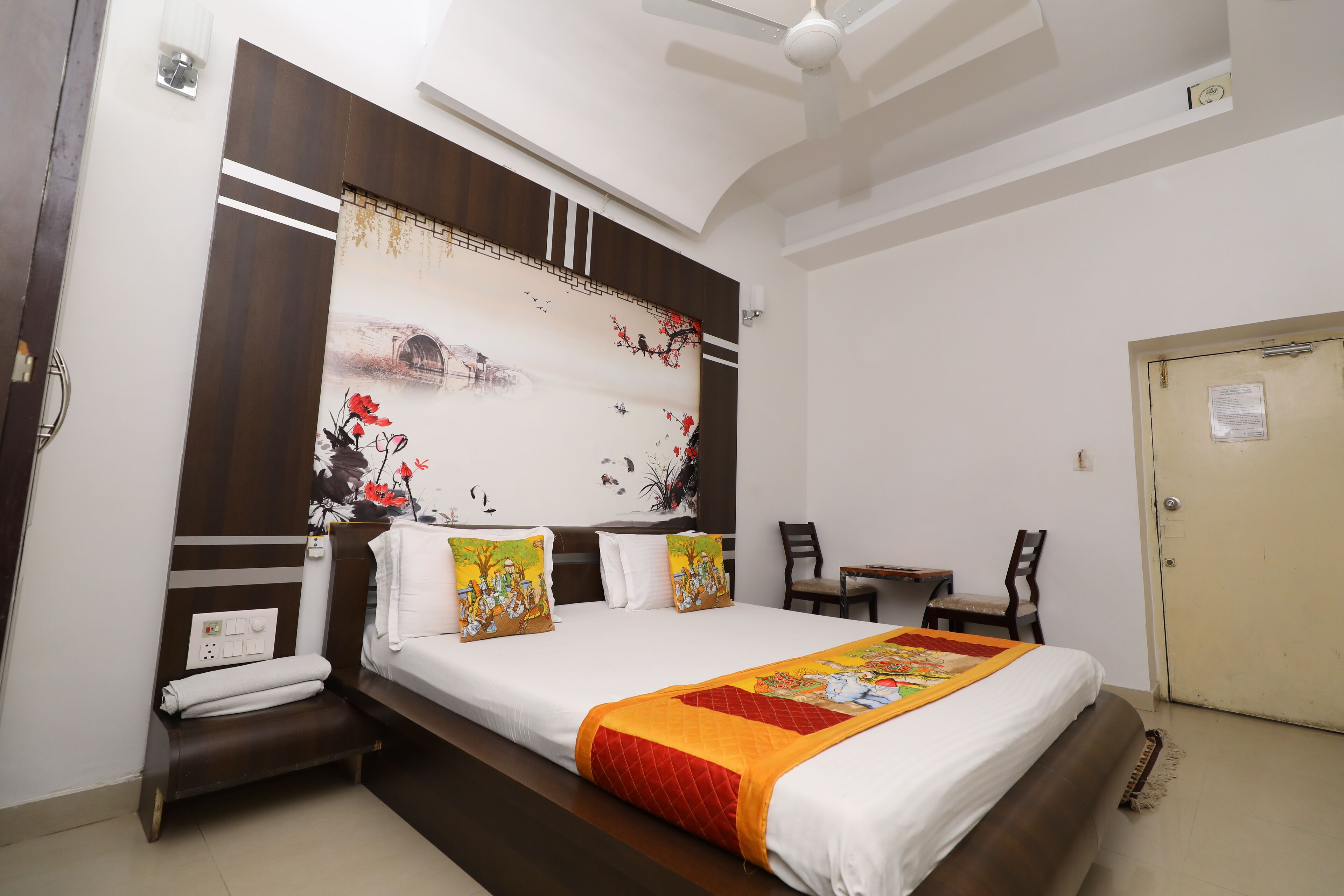 A hotel room with a large bed, a desk, and a chair.