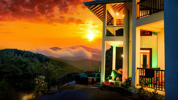 A two-story building with a balcony and a view of a sunset over a mountainous landscape.