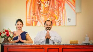 A reception desk with a 'RECEPTION' sign, a Buddha statue, and a painting of a woman in traditional attire.