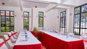 A conference room with long tables, white chairs, and red tablecloths. - Galaxy Inn - Athi River (Athi River)