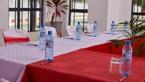 A conference room with a red tablecloth, white chairs, and water bottles on the table. - Galaxy Inn - Athi River (Athi River)