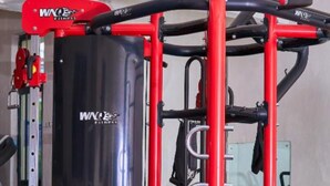 A gym with a red and black workout station, a large black exercise machine, and a trampoline. - Galaxy Inn - Athi River (Athi River)