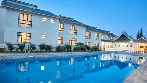 A hotel with a swimming pool, a covered outdoor area, and a building with multiple windows. - Galaxy Inn - Athi River (Athi River)