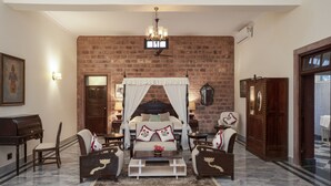 A bedroom with a brick wall, a canopy bed, and a chandelier.