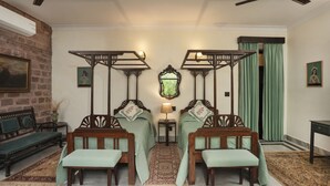 A room with two wooden beds, a bench, a table, and a ceiling fan.