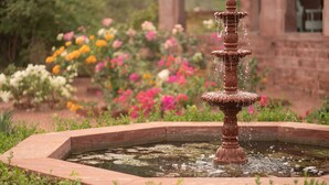 A fountain surrounded by a circular stone border with water flowing from its tiers.