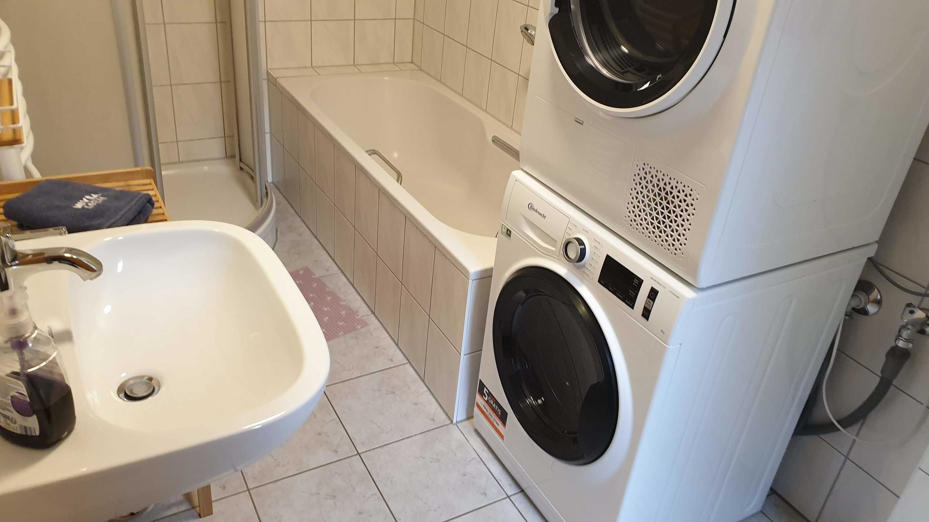 Ein kleines Badezimmer mit Waschbecken, Waschmaschine und Badewanne.