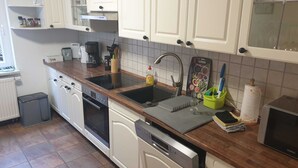 Uma cozinha com armários brancos, uma pia dupla, uma cafeteira e um frasco de detergente.