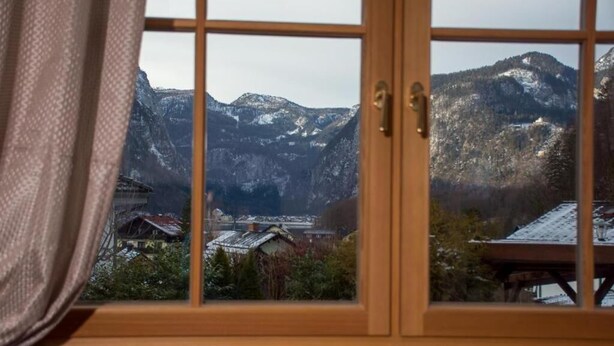 Ein Fenster mit Blick auf schneebedeckte Berge und ein Dorf darunter.