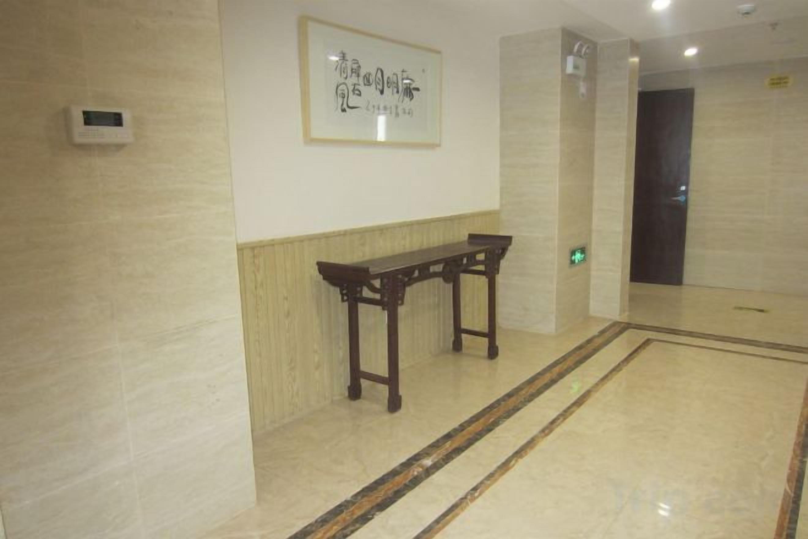 A hallway with a wooden bench, a framed artwork on the wall, and a door at the end.