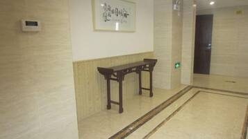 A hallway with a wooden bench, a framed artwork on the wall, and a door at the end.