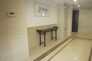 A hallway with a wooden bench, a framed artwork on the wall, and a door at the end. - Yushi Culture City Hotel (Songyang)