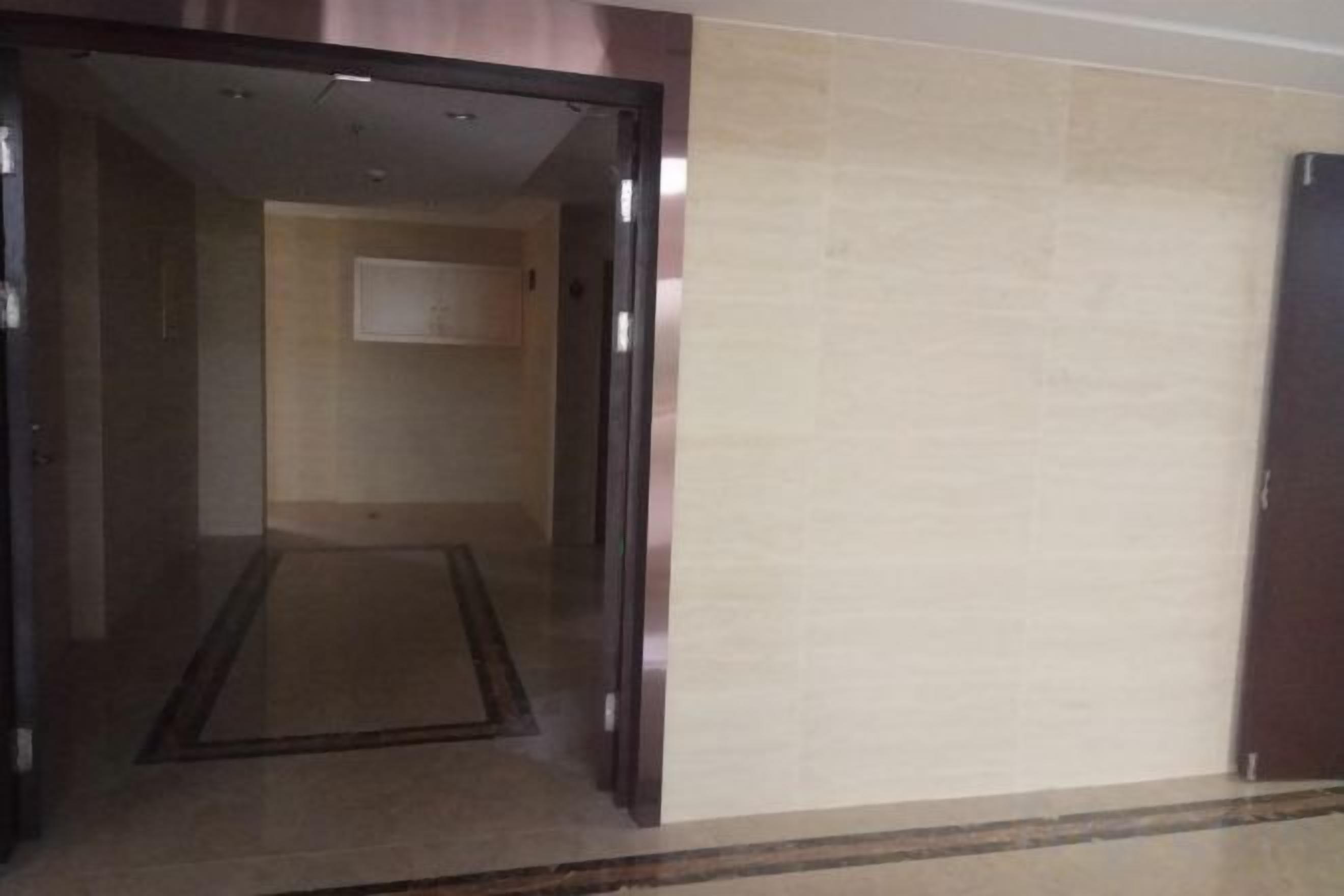 An interior corridor with a carpeted floor and a door leading to another room.