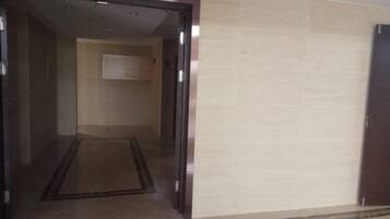 An interior corridor with a carpeted floor and a door leading to another room.