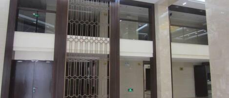 A modern lobby with a central column, glass doors, and a marble floor.