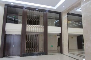 A modern lobby with a central column, glass doors, and a marble floor. - Yushi Culture City Hotel (Songyang)