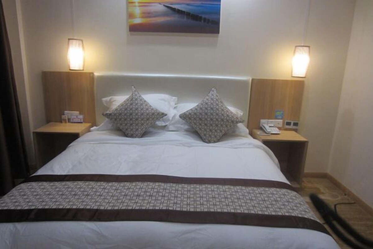 Ein Hotelzimmer mit einem großen Bett, zwei Nachttischen, einem Beistelltisch und einem Bild an der Wand.