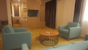 Een kamer met twee banken, een salontafel, een televisie en een gordijn.
